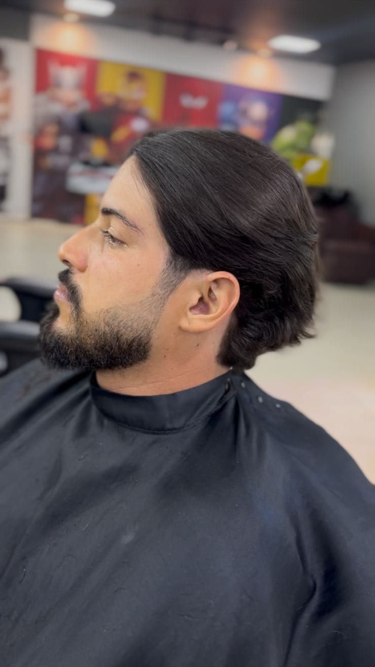 Cabelo longo penteado para trás com barba cheia alinhada